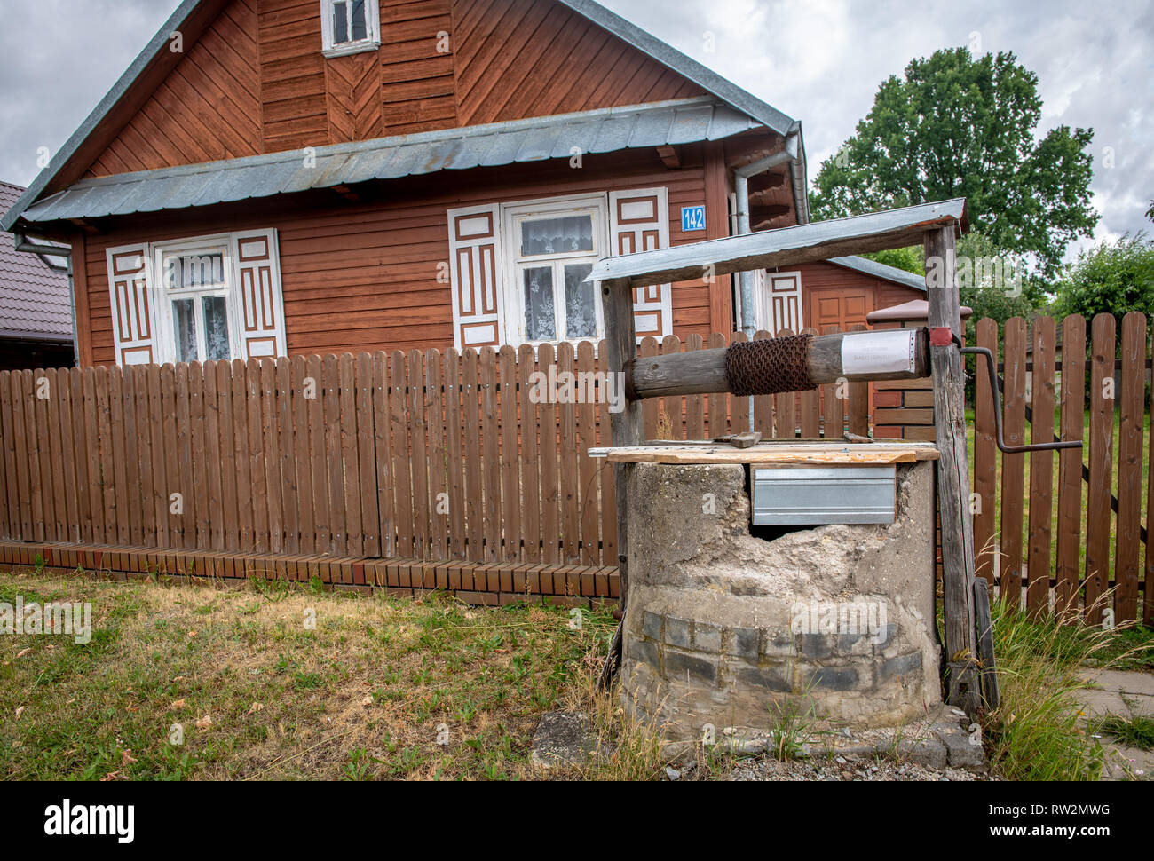 Acqua siede ben coperta in cantiere con cabina-casa in stile decorativo con otturatori dietro di esso in Trześcianka "Terra di persiane aperte", POLONIA, Foto Stock