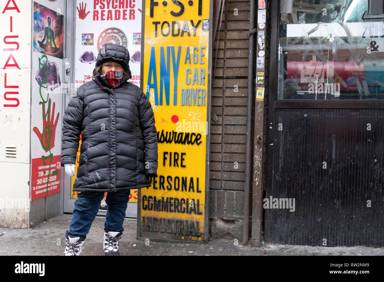 Una donna in una pesante soprabito mani volantini davanti ad un lettore psichica dell'ufficio in una fredda giornata invernale. A Roosevelt Ave. in Jackson Heights, New York. Foto Stock