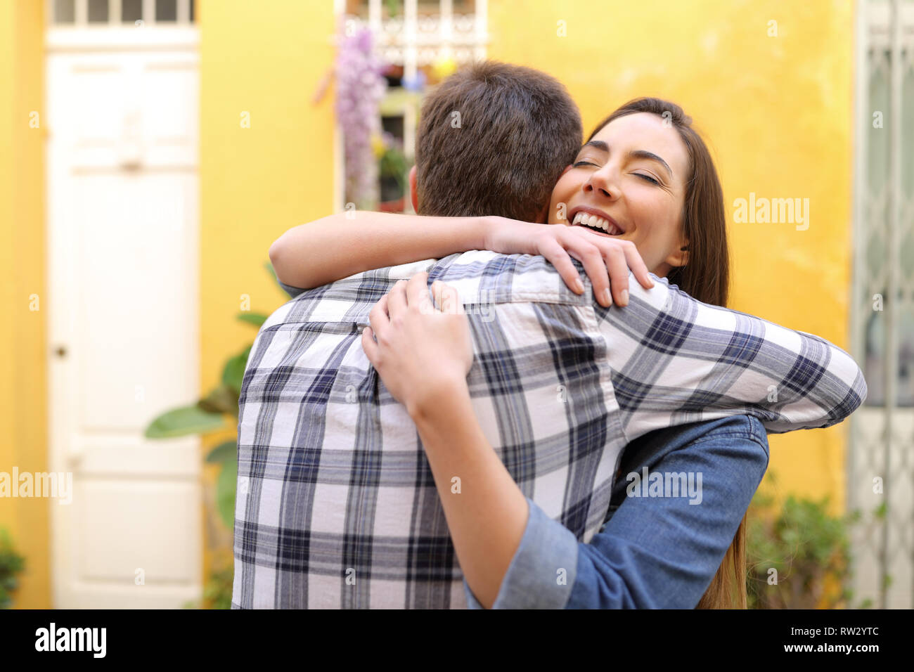 Felice coppia o amici abbracciando dopo un incontro in una strada Foto Stock