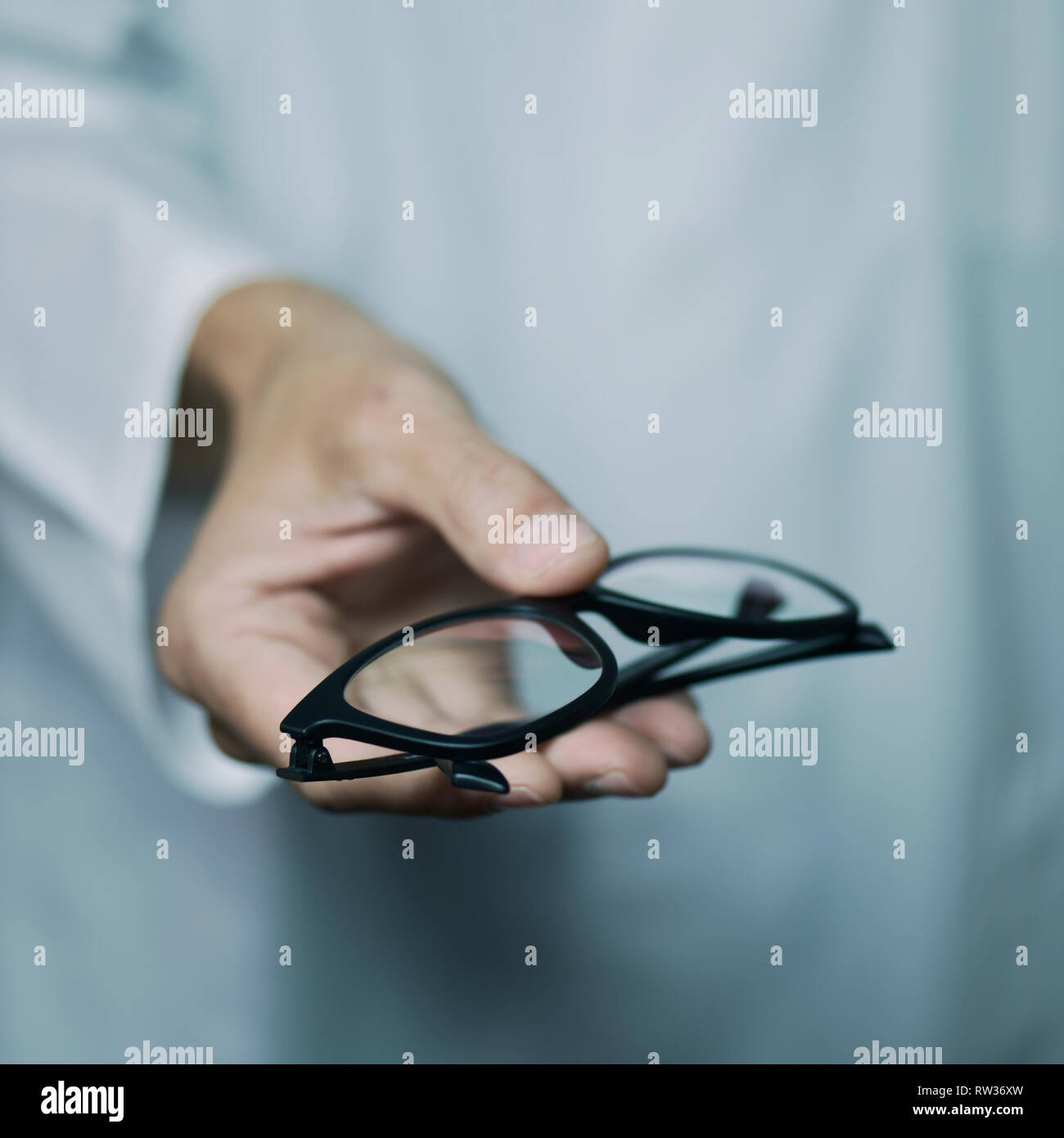 Primo piano di una giovane ottico caucasica uomo in camice bianco di portare un paio di occhiali per l'osservatore Foto Stock