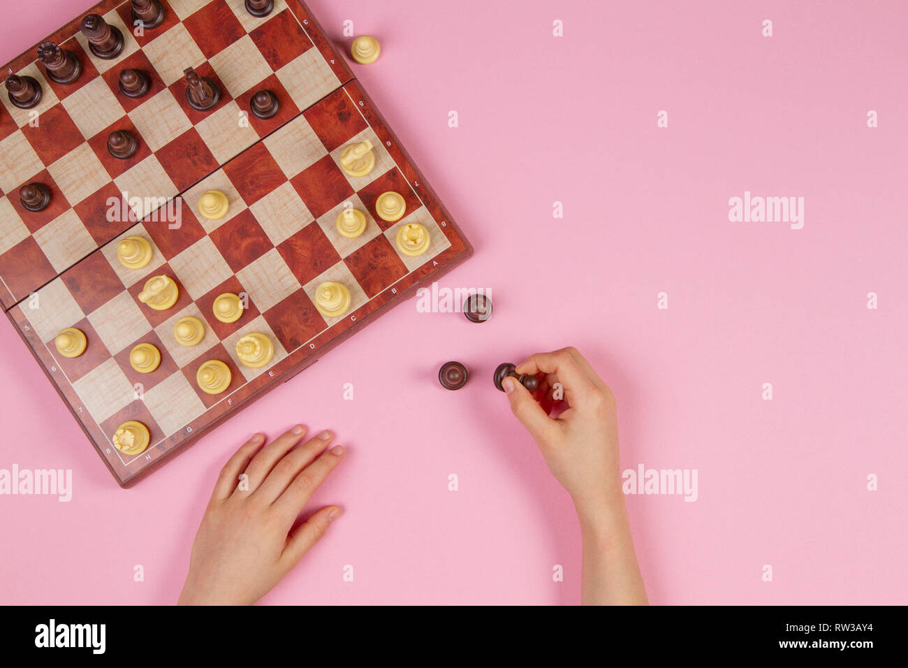 Il capretto con le mani su una scacchiera giocare a scacchi gioco su sfondo rosa, vista dall'alto Foto Stock