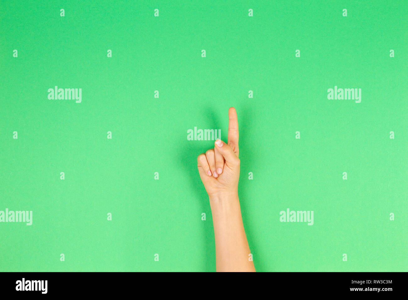 Kid mano che mostra un dito su sfondo verde Foto Stock