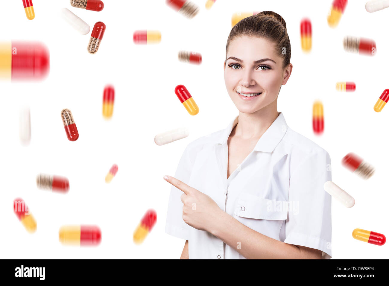 Giovane medico donna in piedi tra pillole pioggia su sfondo bianco. Foto Stock