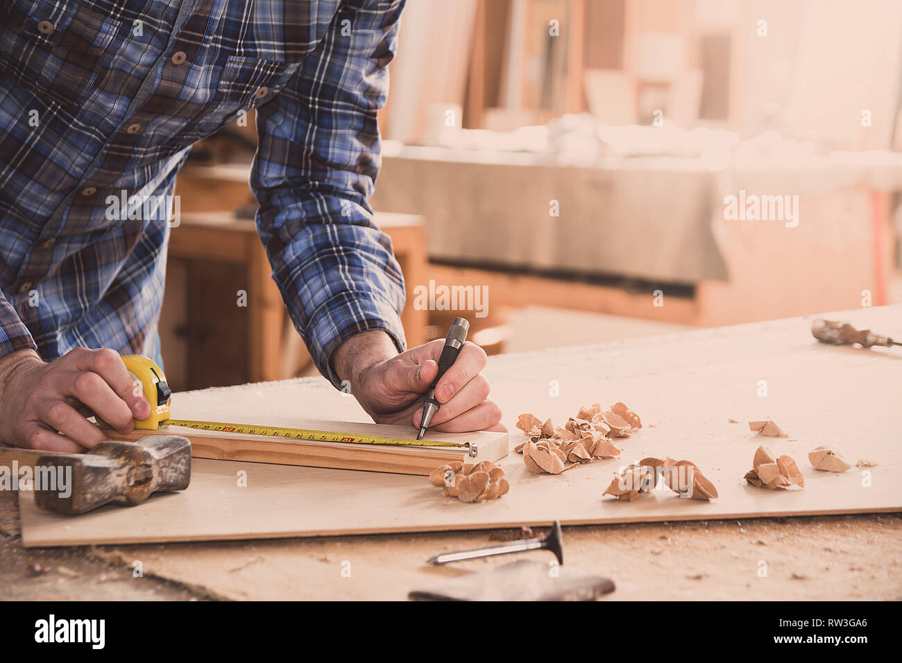 Carpenter lavora con metro a nastro, il metro o la regola di prendere misure di legno utilizzando una matita. Workshop sullo sfondo. Carpenter workbench. Foto Stock