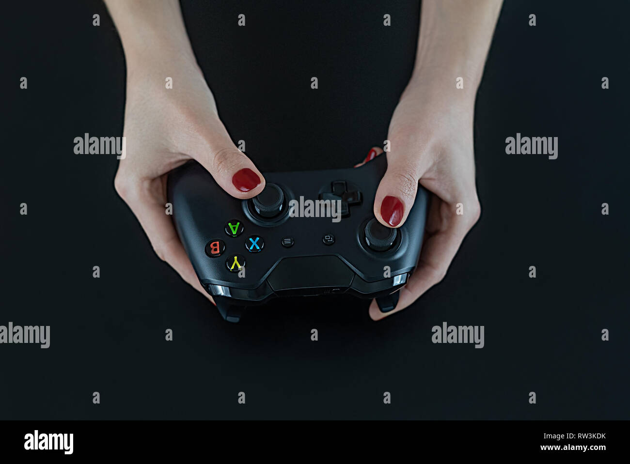 Vista superiore della donna le mani con il rosso smalto per unghie sulle dita tenendo un logo moderna senza controller di gioco per la riproduzione di video digitali isolati giochi su nero Foto Stock