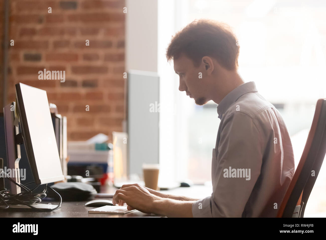 Grave imprenditore focalizzato la digitazione di lavoro sul computer in ufficio Foto Stock