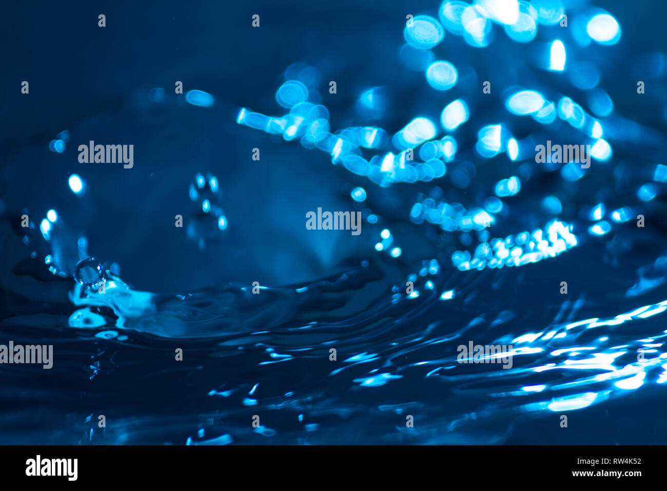 Splash di gocce di acqua su una superficie di acqua colorata con inchiostro celesti. Concetto di purezza, pulizia e conservazione delle risorse non rinnovabili. Abstr Foto Stock
