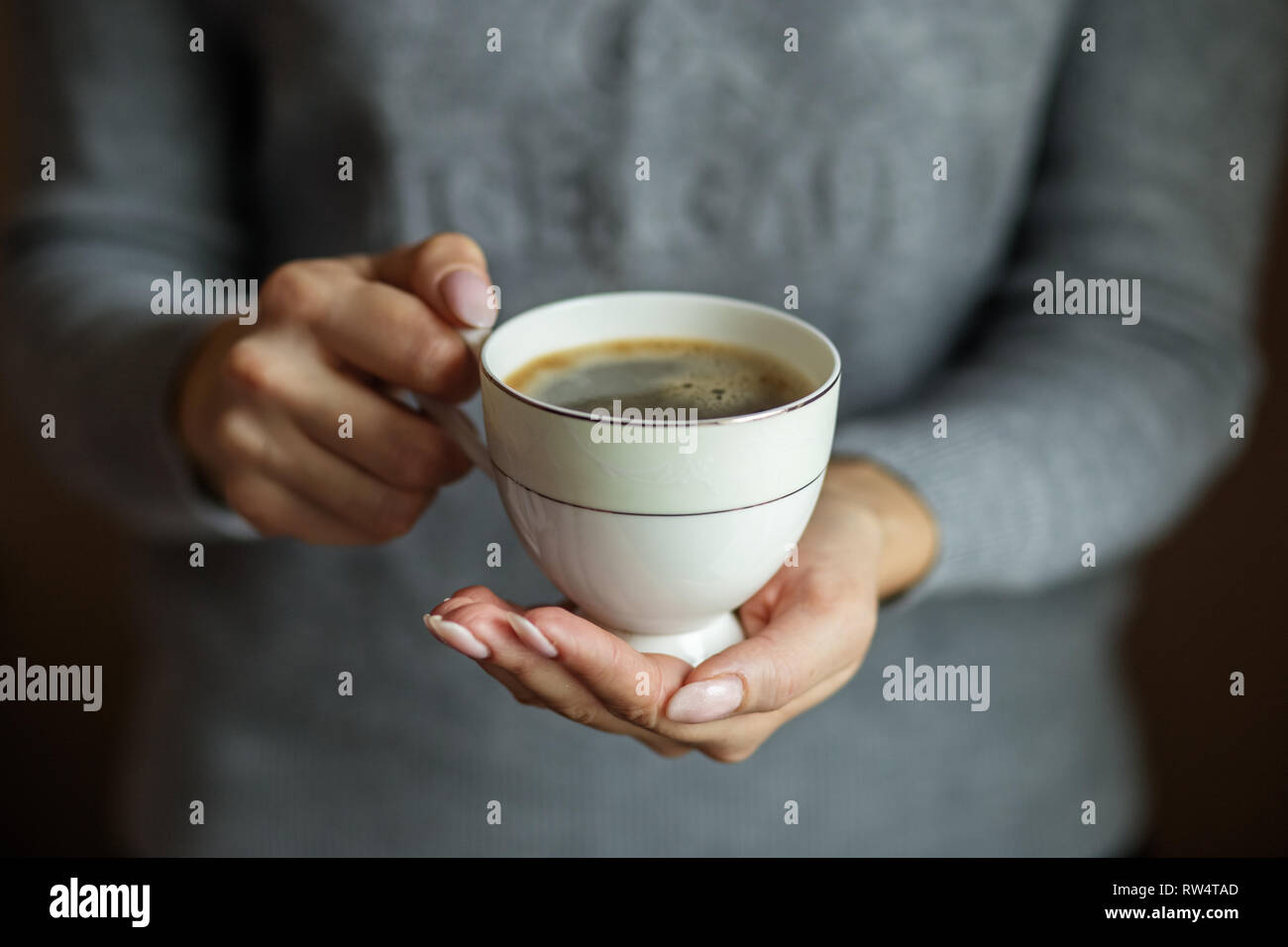 Una tazza di delizioso caffè in mani femminili. Concetto di bevande, stile di vita, lavoro, sfondo Foto Stock