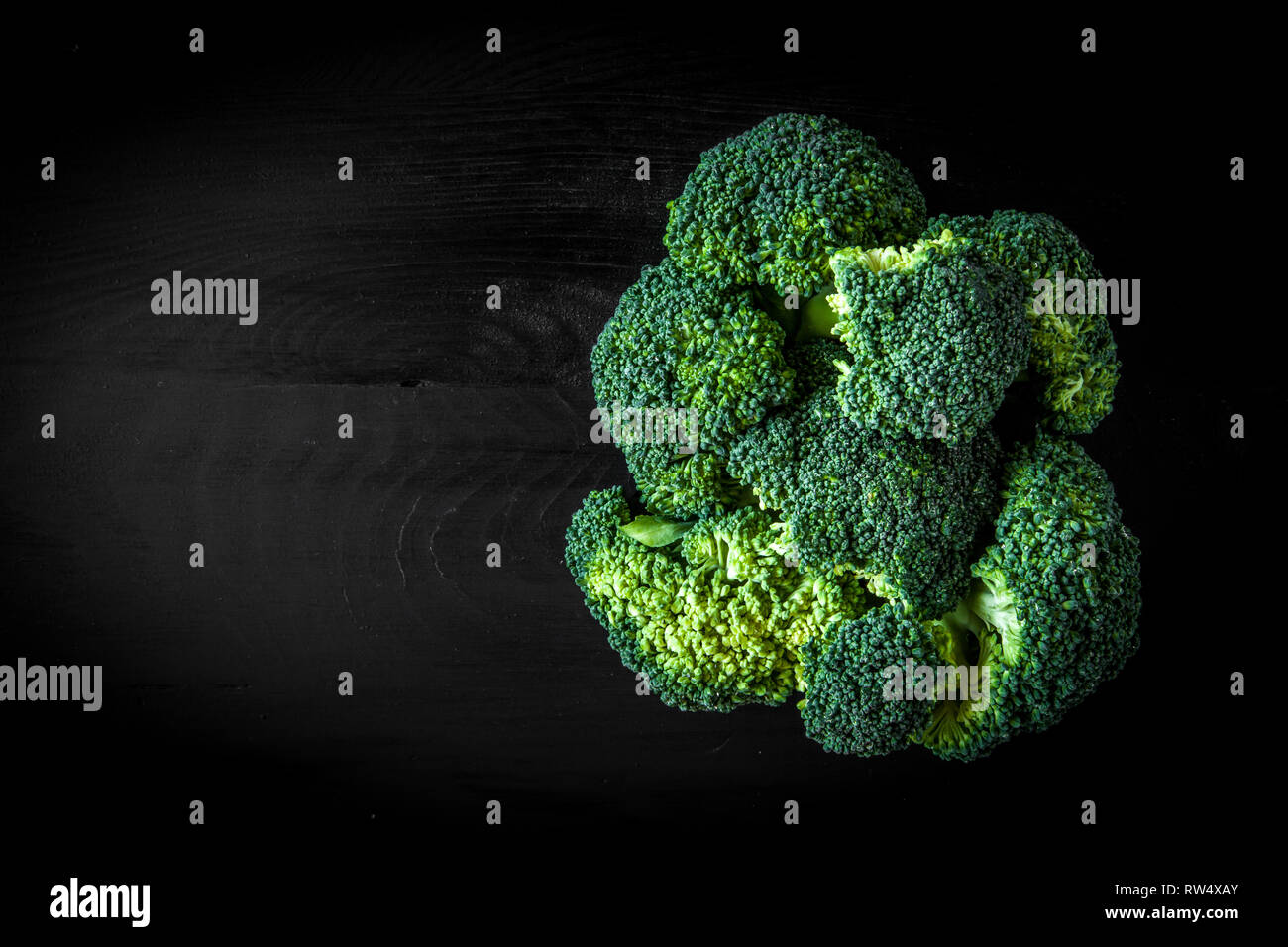 Brokkoli isolate su legno scuro board su sfondo nero Foto Stock