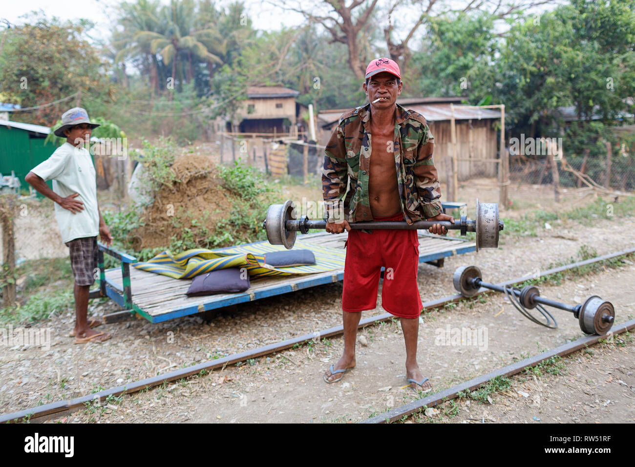 Gli uomini posizionando la piattaforma di bambù sulle ruote, il treno di bambù; Battambang, Cambogia Foto Stock