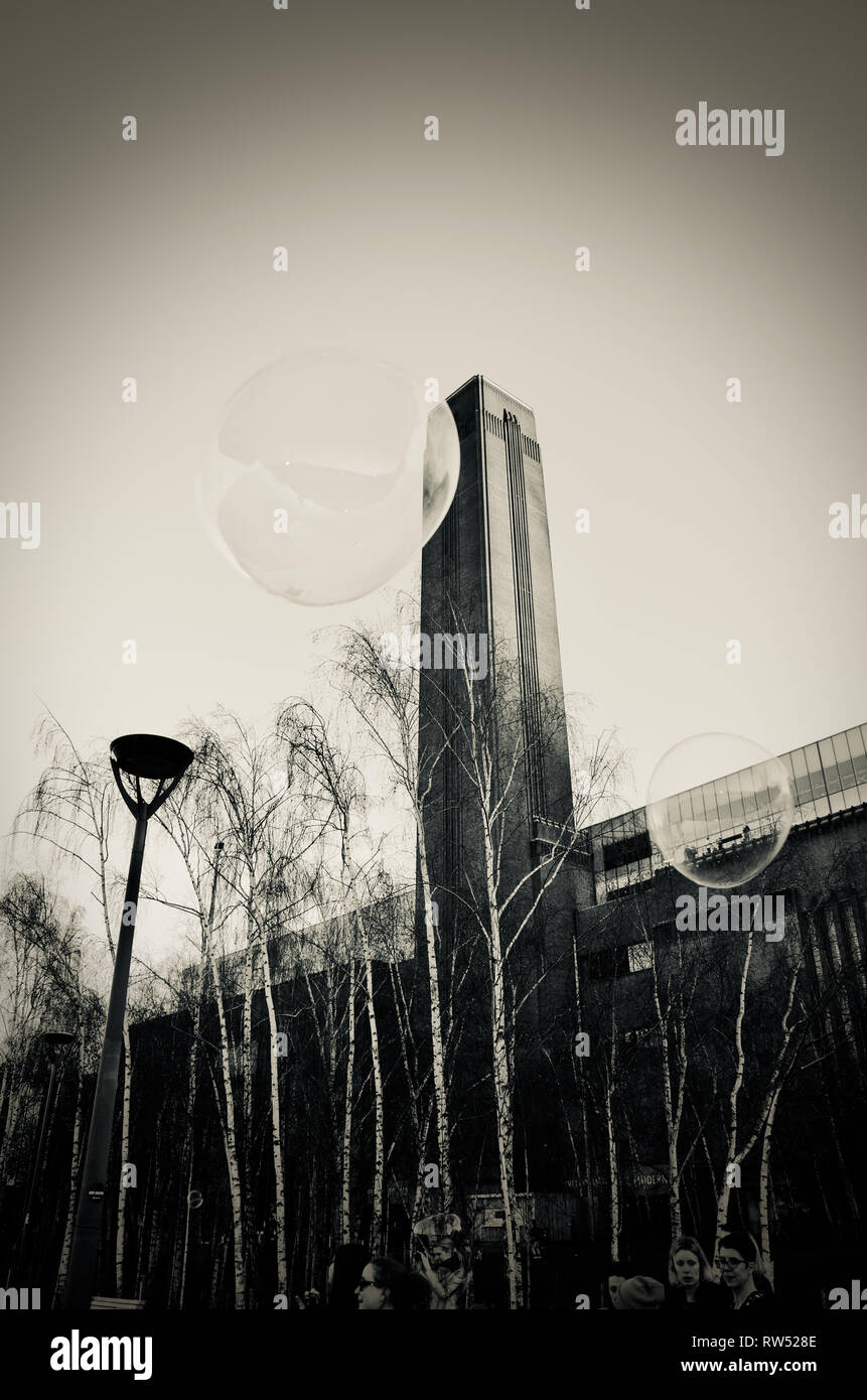 Bolle da street intrattenitore galleggianti intorno alla torre di Tate Modern sul Tamigi Embankment, Londra, Regno Unito. Vignette monocromatici tono di selenio Foto Stock