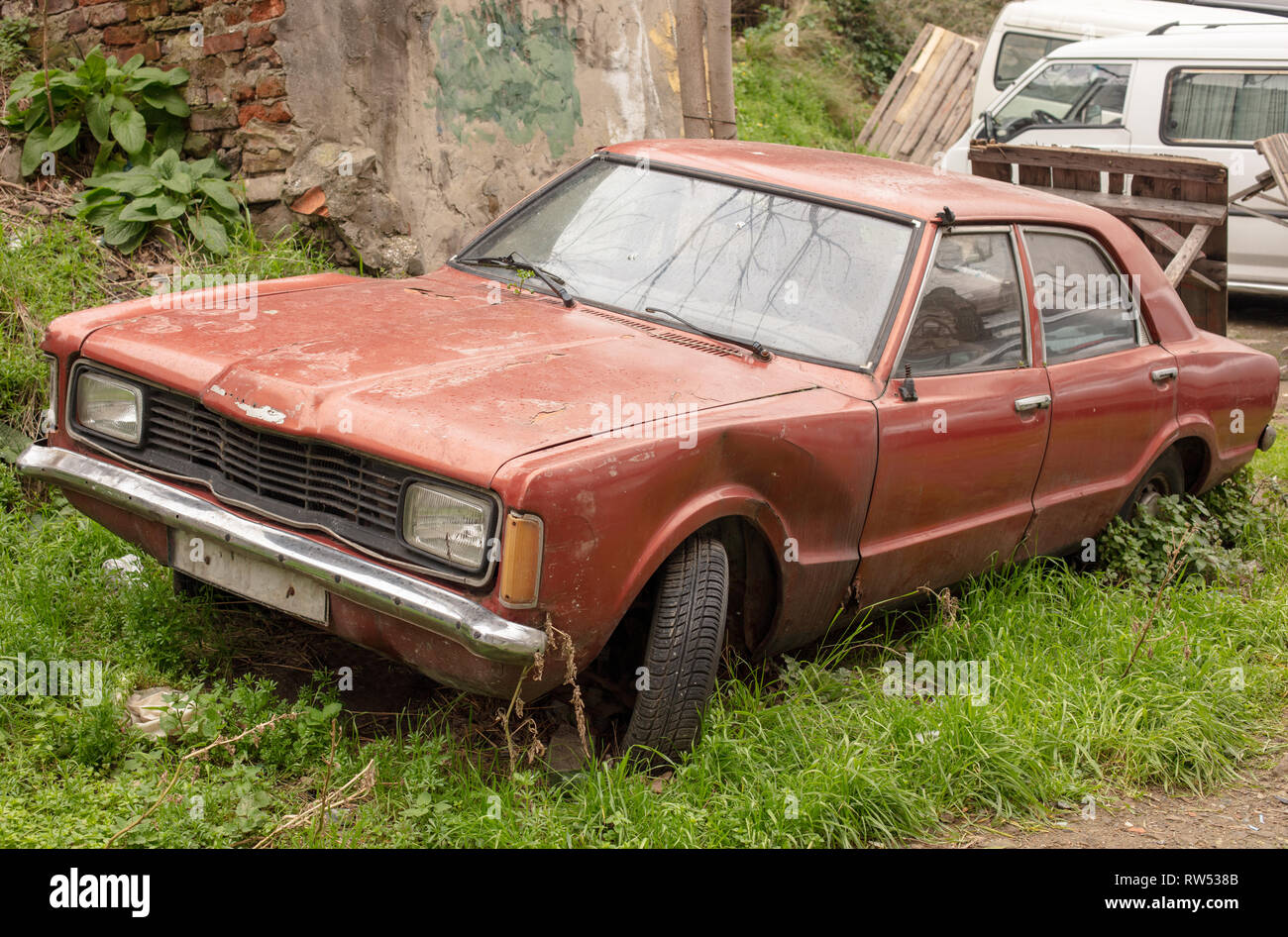 Vecchio scartato rusty auto su erba verde dello sfondo. Rotto e dimenticato. Un vecchio scartato arrugginita fuori i rottami di automobile che è stato abbandonato Foto Stock