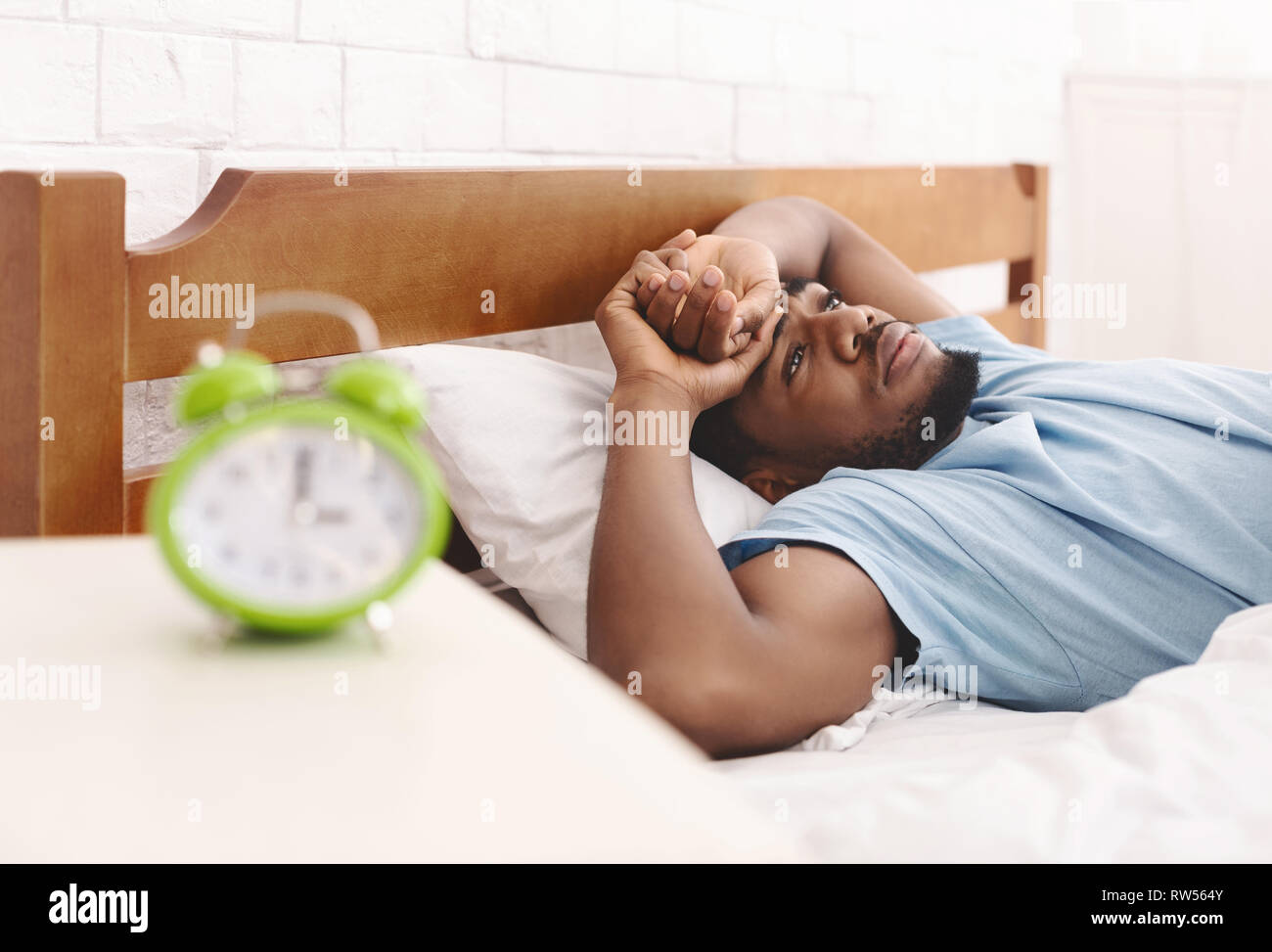 Uomo nero nel letto che soffrono di insonnia e disturbi del sonno Foto Stock