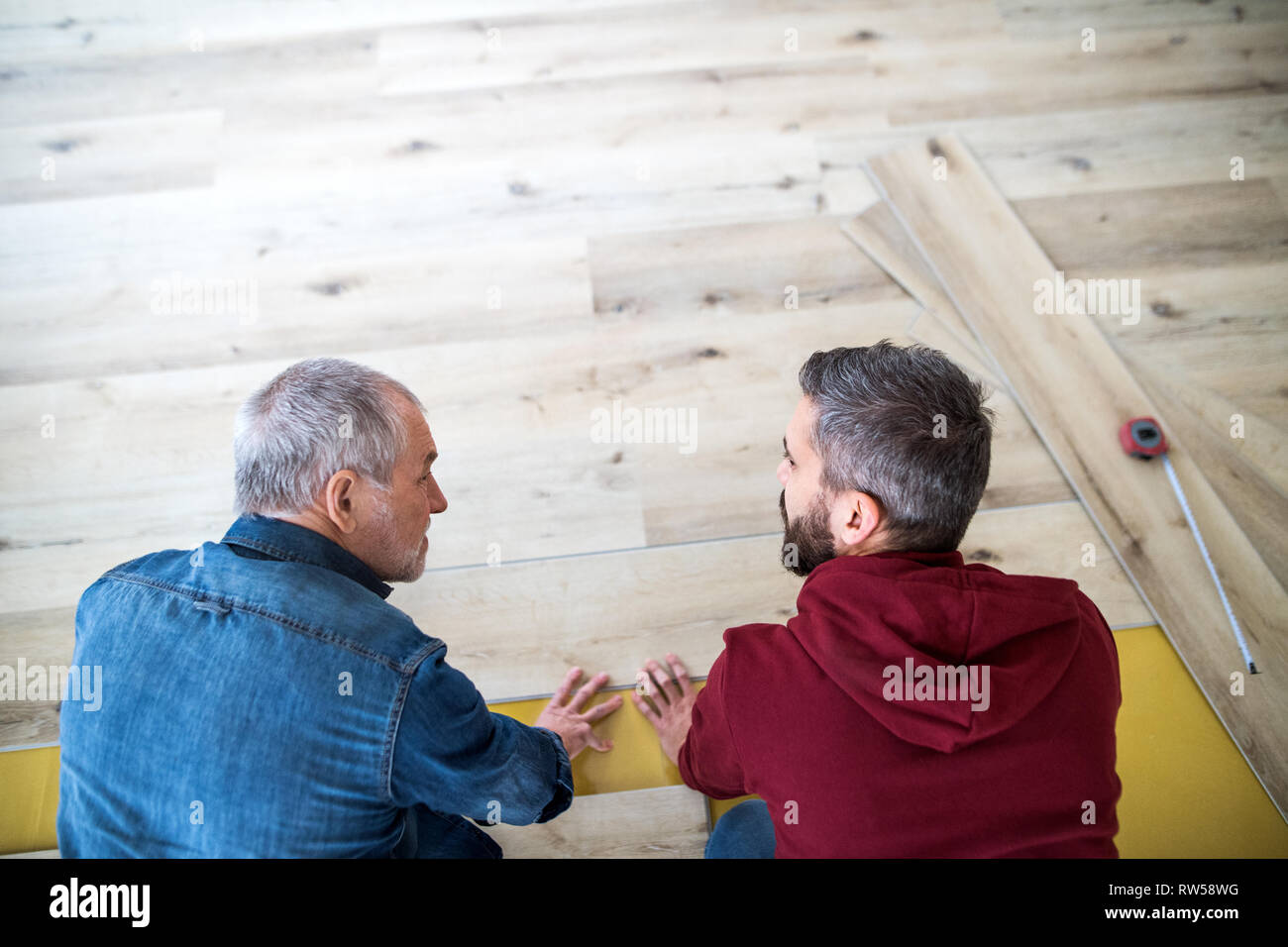 Un uomo maturo con il suo anziano padre la posa di pavimenti in legno, un nuovo concetto di casa. Foto Stock