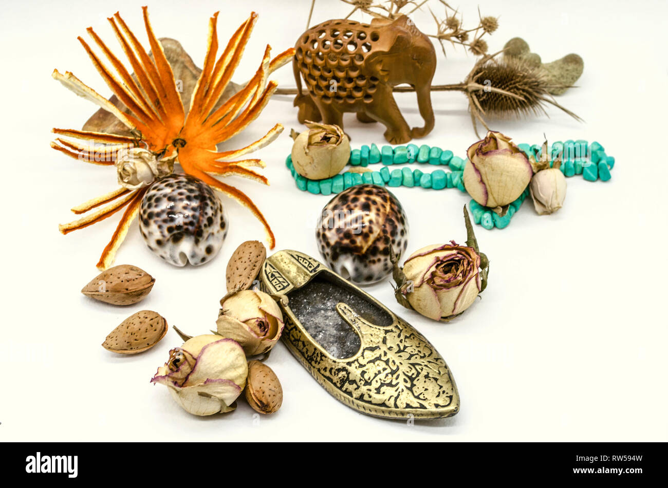 Vecchi souvenir orientale,l'elefante in legno statuetta, perline di turchese, pattino in ottone a forma di posacenere, asciugare le gemme, spine, gusci su sfondo bianco Foto Stock