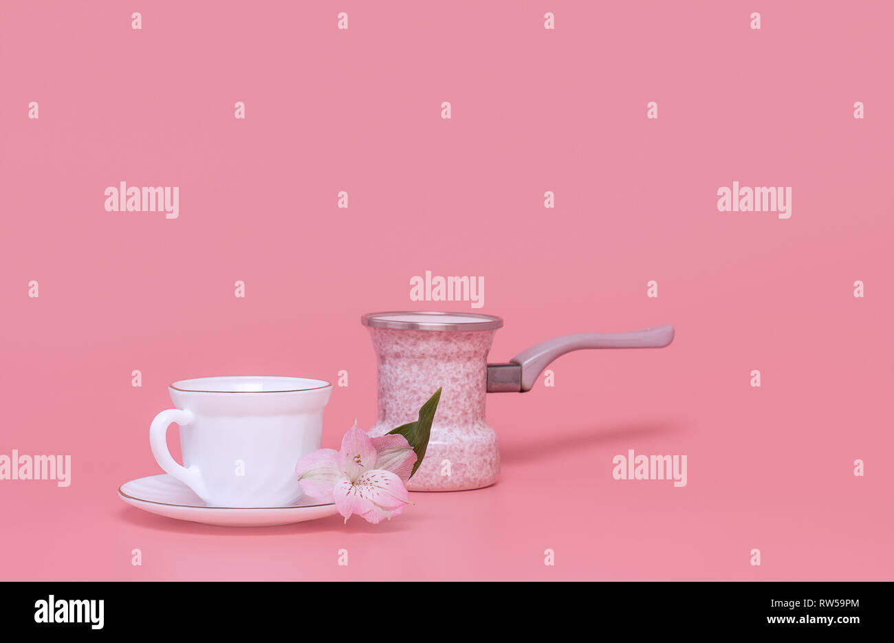 Stile minimalista. Una tazza di caffè e bollitore per il caffè su un sfondo rosa, turka caffè Foto Stock