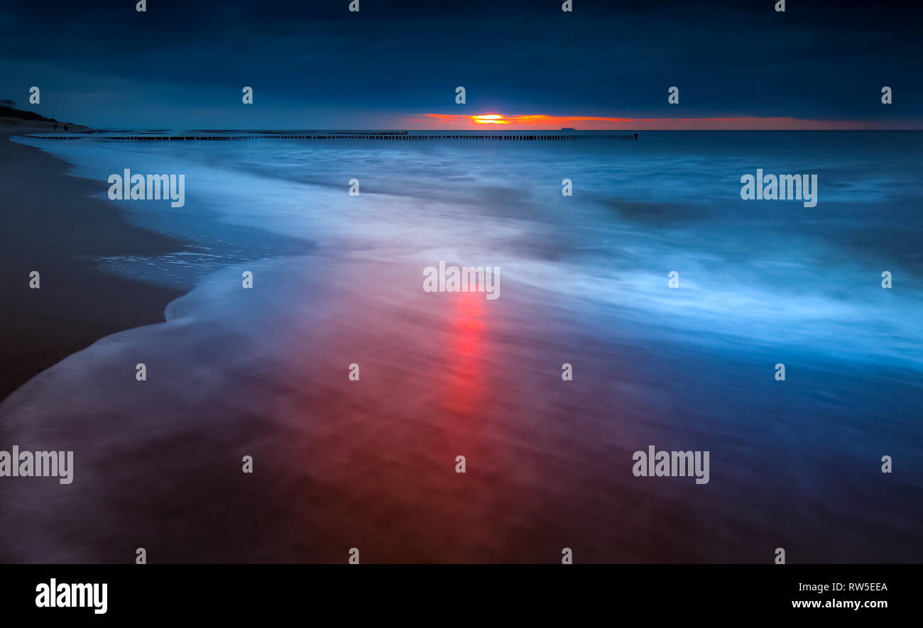 La luce del sole bacia l'onda al litorale rostock Warnemünde, tramonto al mare Foto Stock