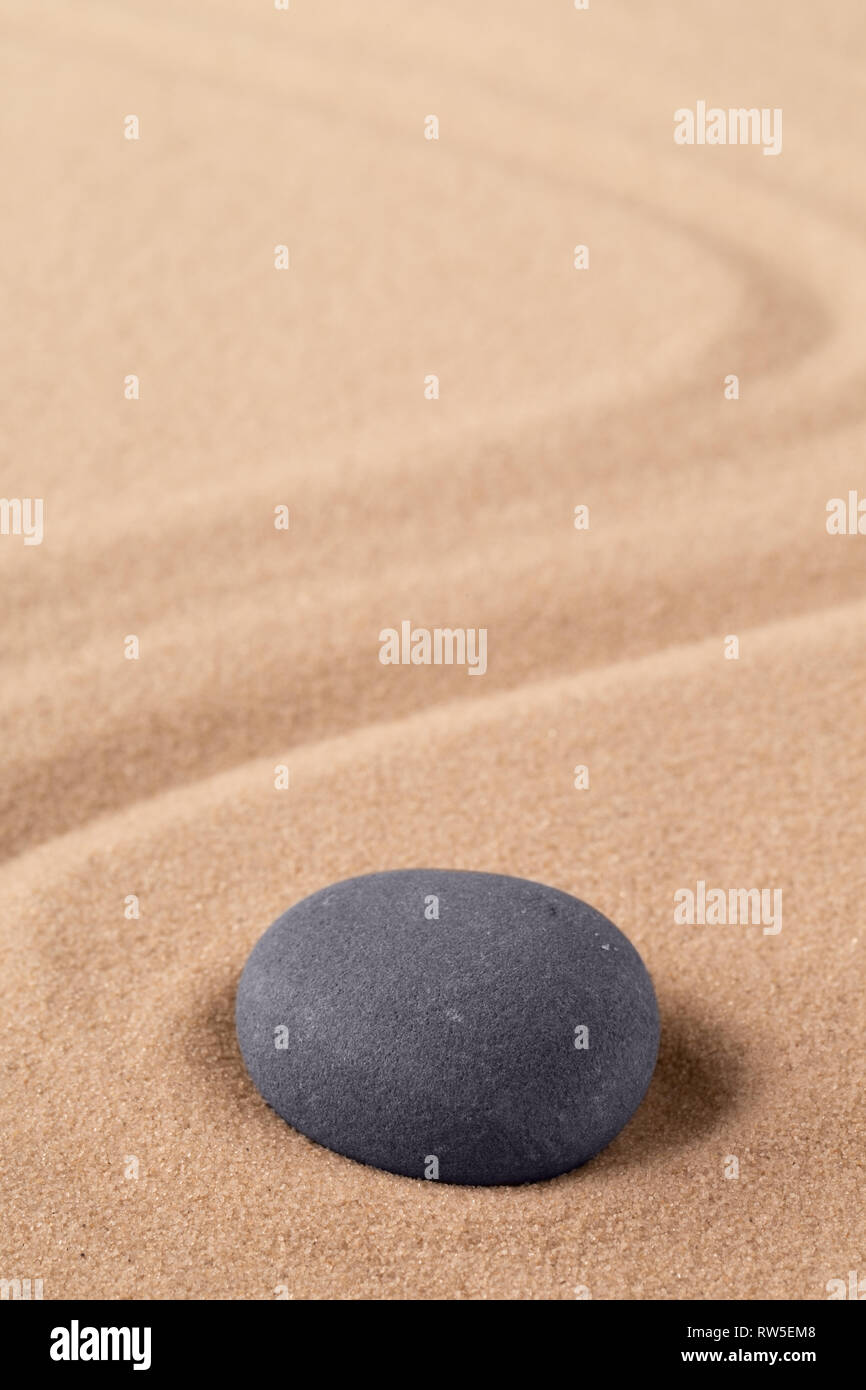 Meditazione Zen Stone per la messa a fuoco e concentrato per un uscire la pace della mente. Spirituale di sabbia rastrellata texture di sfondo. Concetto di armonia e purezza di spirito Foto Stock