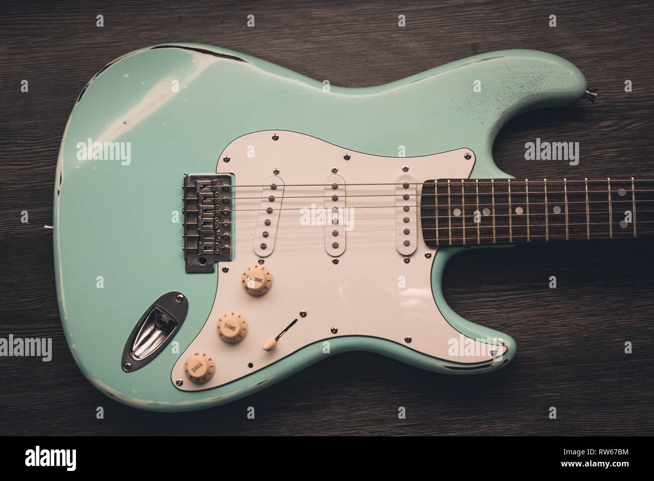 Luce verde blu chitarra elettrica marrone contro uno sfondo di legno. Retrò anima musicale guitar Foto Stock
