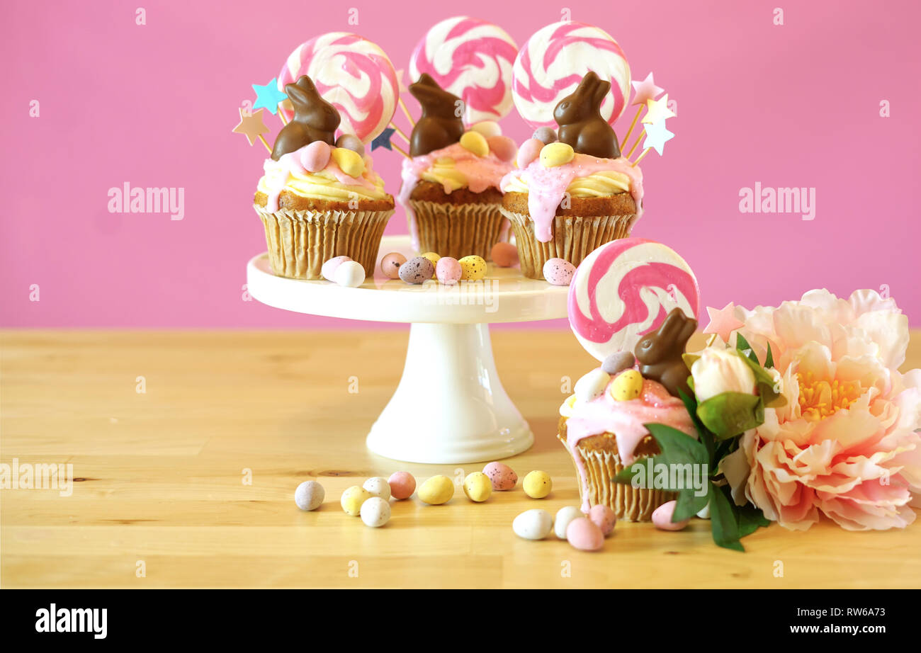 Pasqua tema candy land tortini di gocciolamento decorate con cioccolato coniglietti in parte messa in tavola. Foto Stock