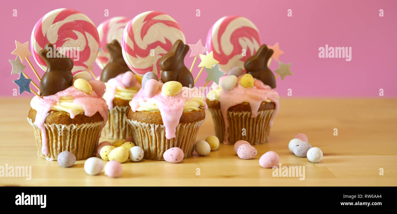 Pasqua tema candy land tortini di gocciolamento decorate con cioccolato coniglietti in parte messa in tavola. Foto Stock