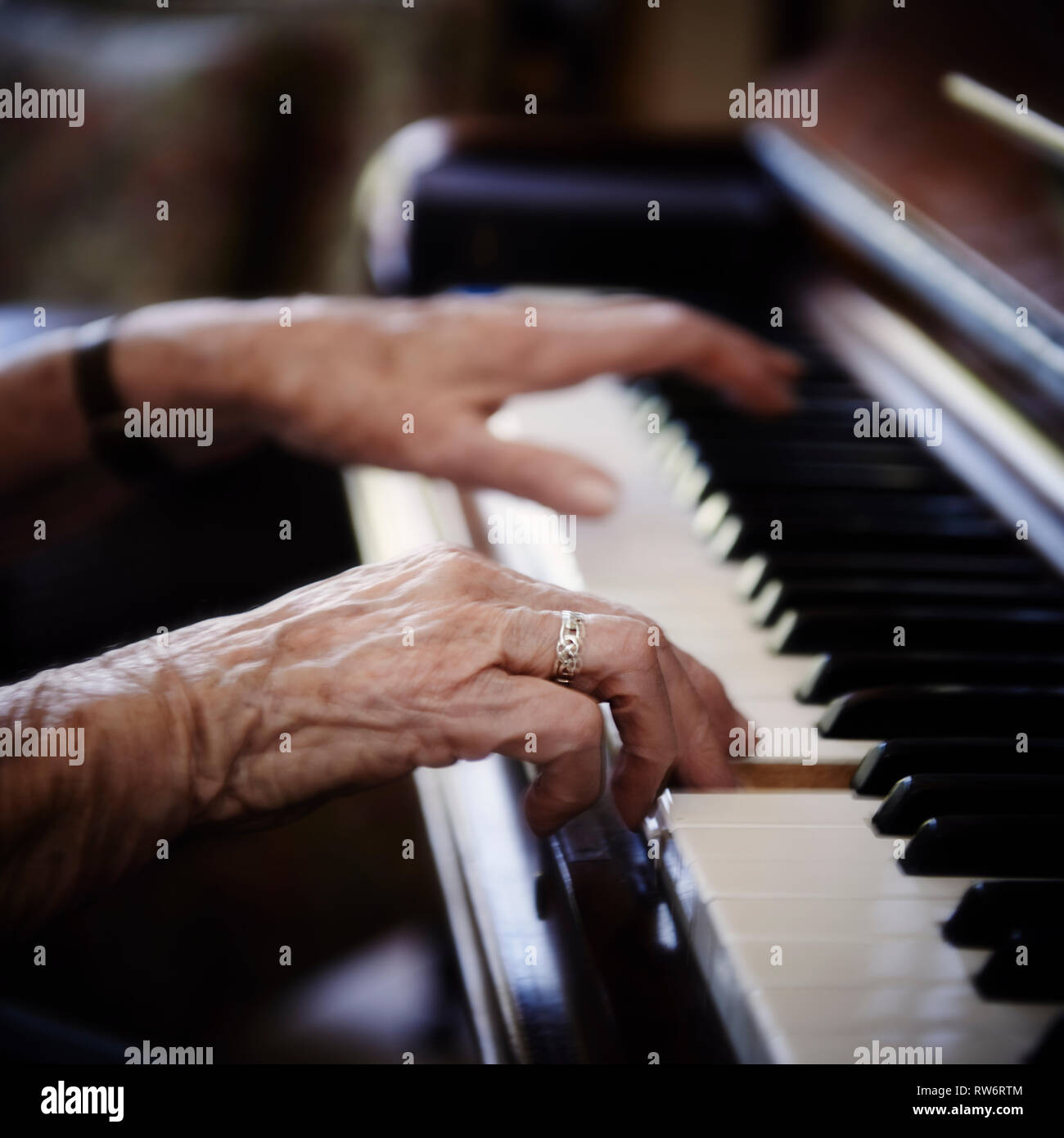Novantadue anni di Jean McDougall suona il pianoforte nella sua casa. La sua bella textured mani volare attraverso i tasti del pianoforte. Foto Stock