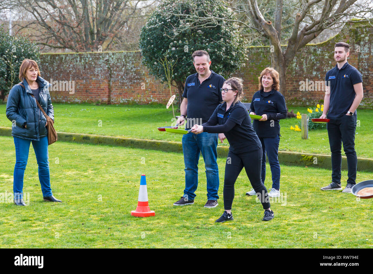 Christchurch, Dorset, Regno Unito. Mar 5, 2019. Il capovolgimento del buon divertimento era da tutti a Christchurch frittelle sul padiglione pancake race il Martedì Grasso. Le squadre che prendono parte a pancake race - donna flipping crêpe in padella. Credito: Carolyn Jenkins/Alamy Live News Foto Stock