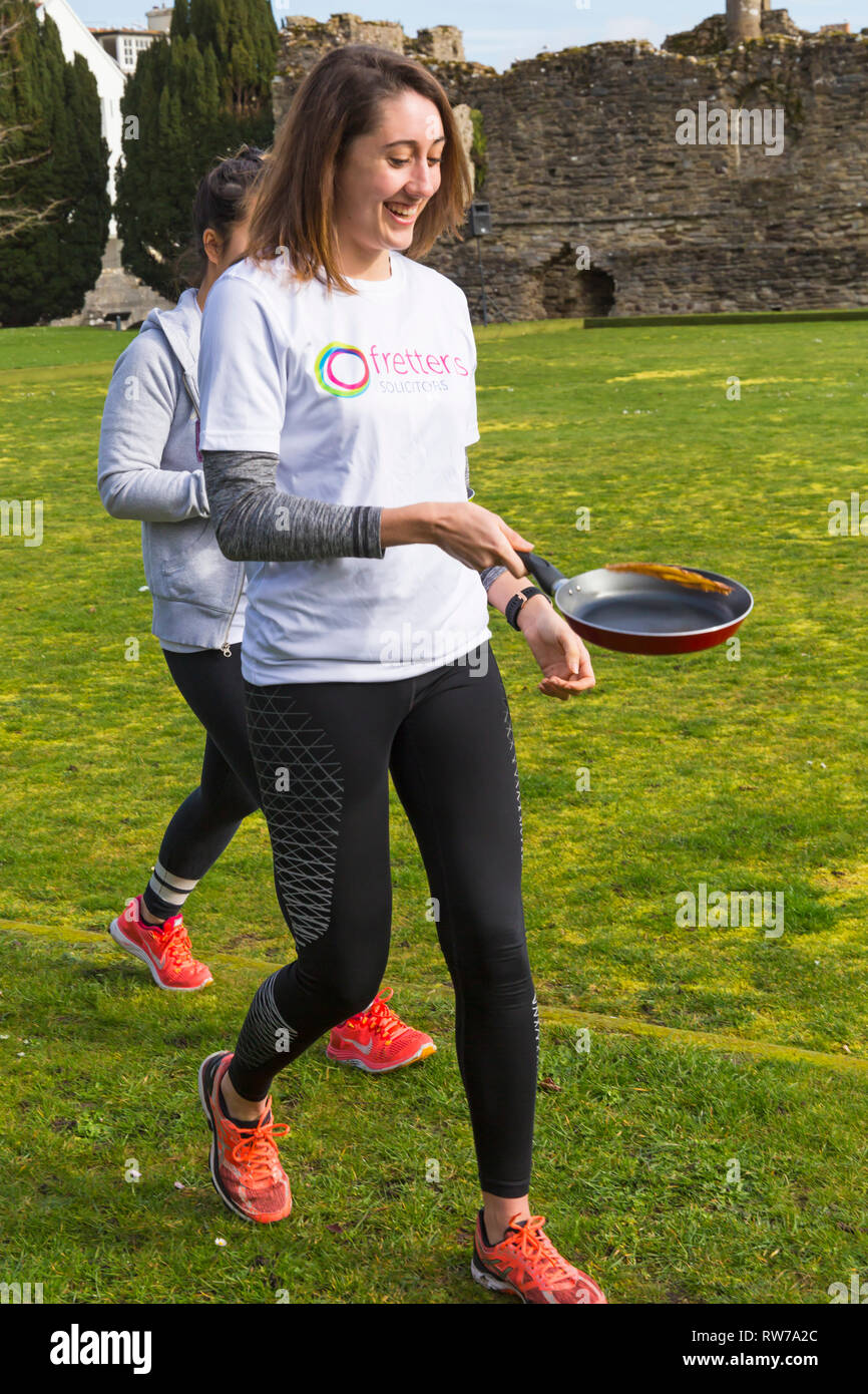 Christchurch, Dorset, Regno Unito. Mar 5, 2019. Il capovolgimento del buon divertimento era da tutti a Christchurch frittelle sul padiglione pancake race il Martedì Grasso. Giovane donna tossing pancake e in esecuzione. Credito: Carolyn Jenkins/Alamy Live News Foto Stock