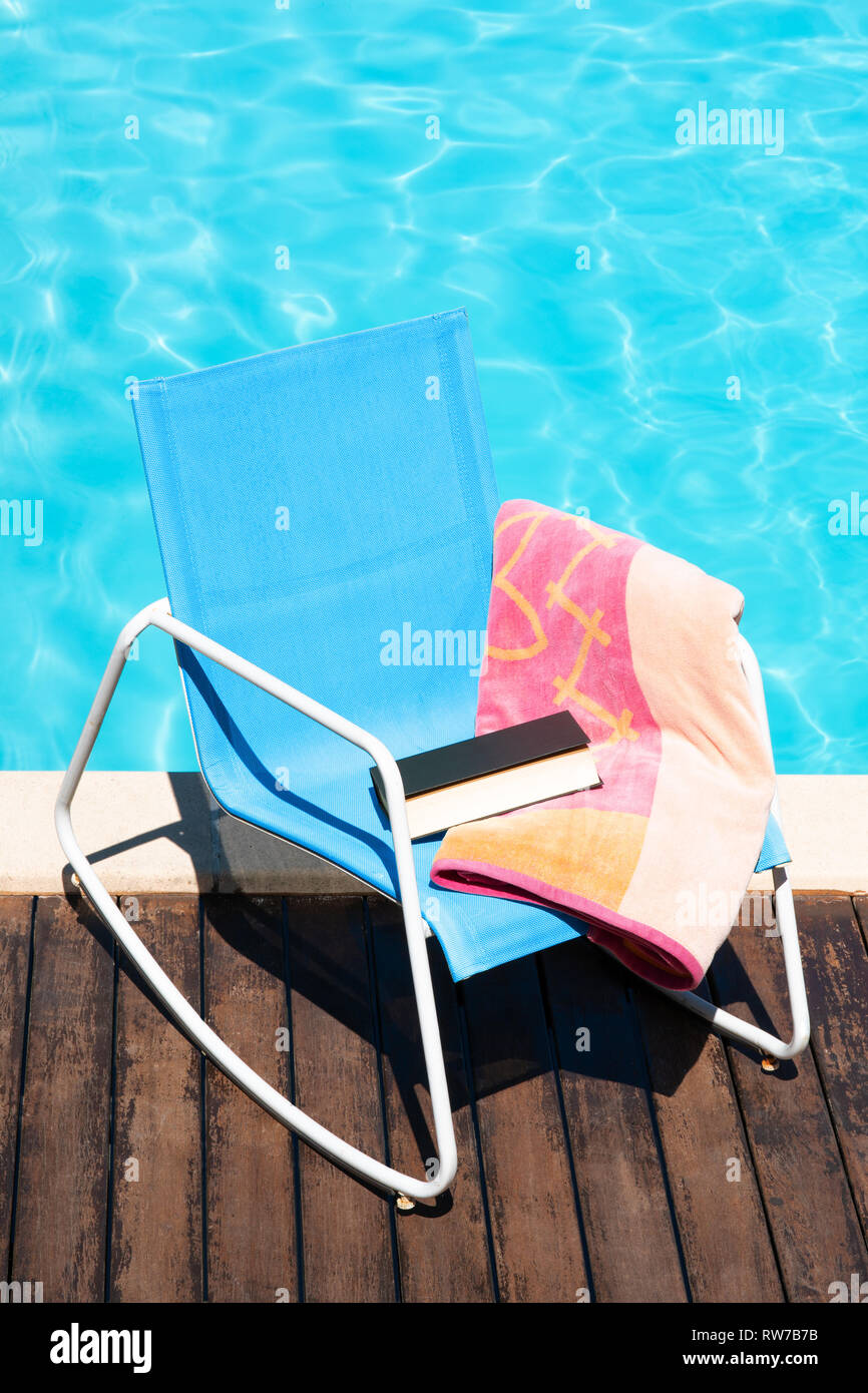 Rilassante concetto d'estate. Scena di sun sedia con telo da spiaggia e prenota sulla piscina Foto Stock