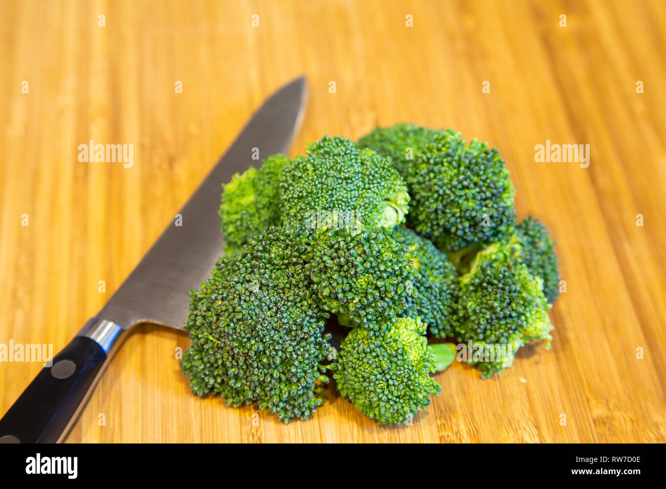 Fresche, materie broccoli su un legno tagliere con un coltello chef Foto Stock