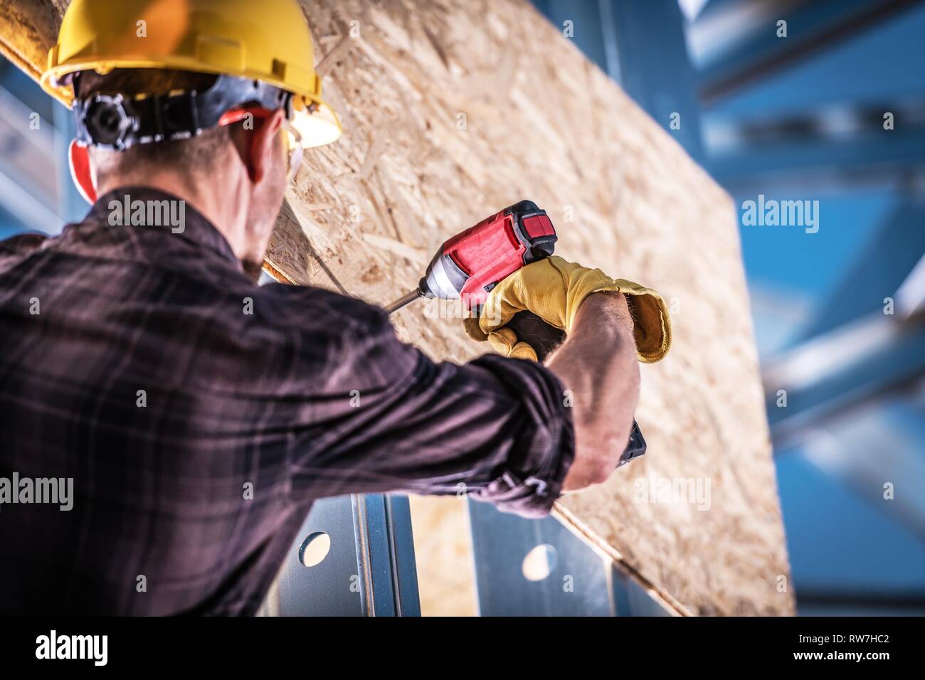 Caucasian lavoratore edile di installare il legno compensato per la costruzione di scheletro. Foto Stock