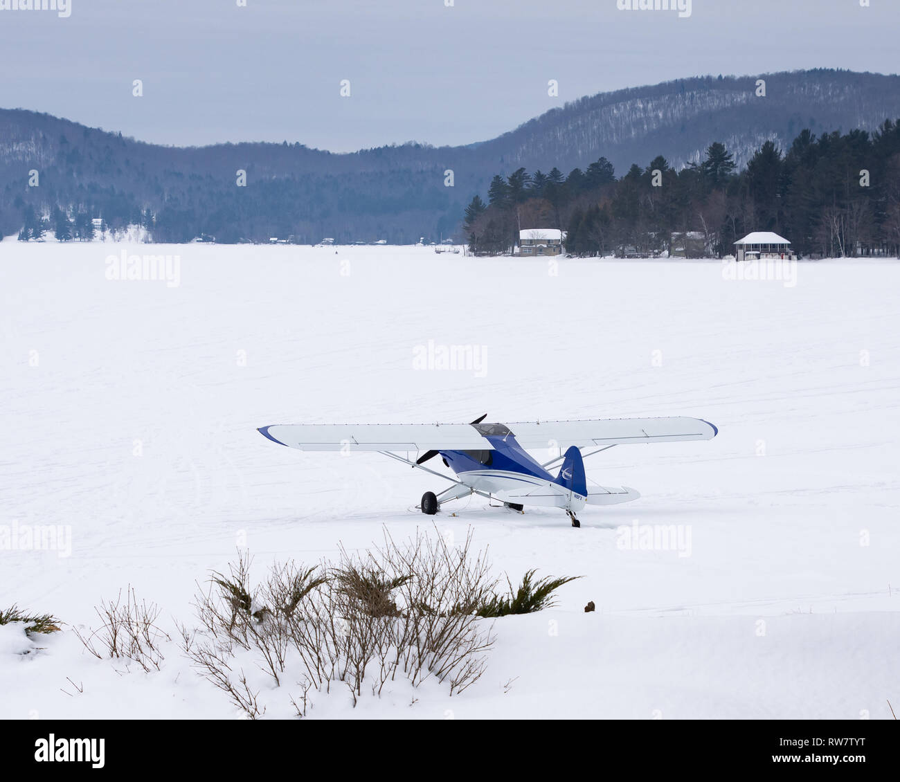 Un carbonio sperimentale Cub modello di Piper Cub aereo su sci parcheggiato su neve e ghiaccio sul Lago Pleasant, NY USA Foto Stock