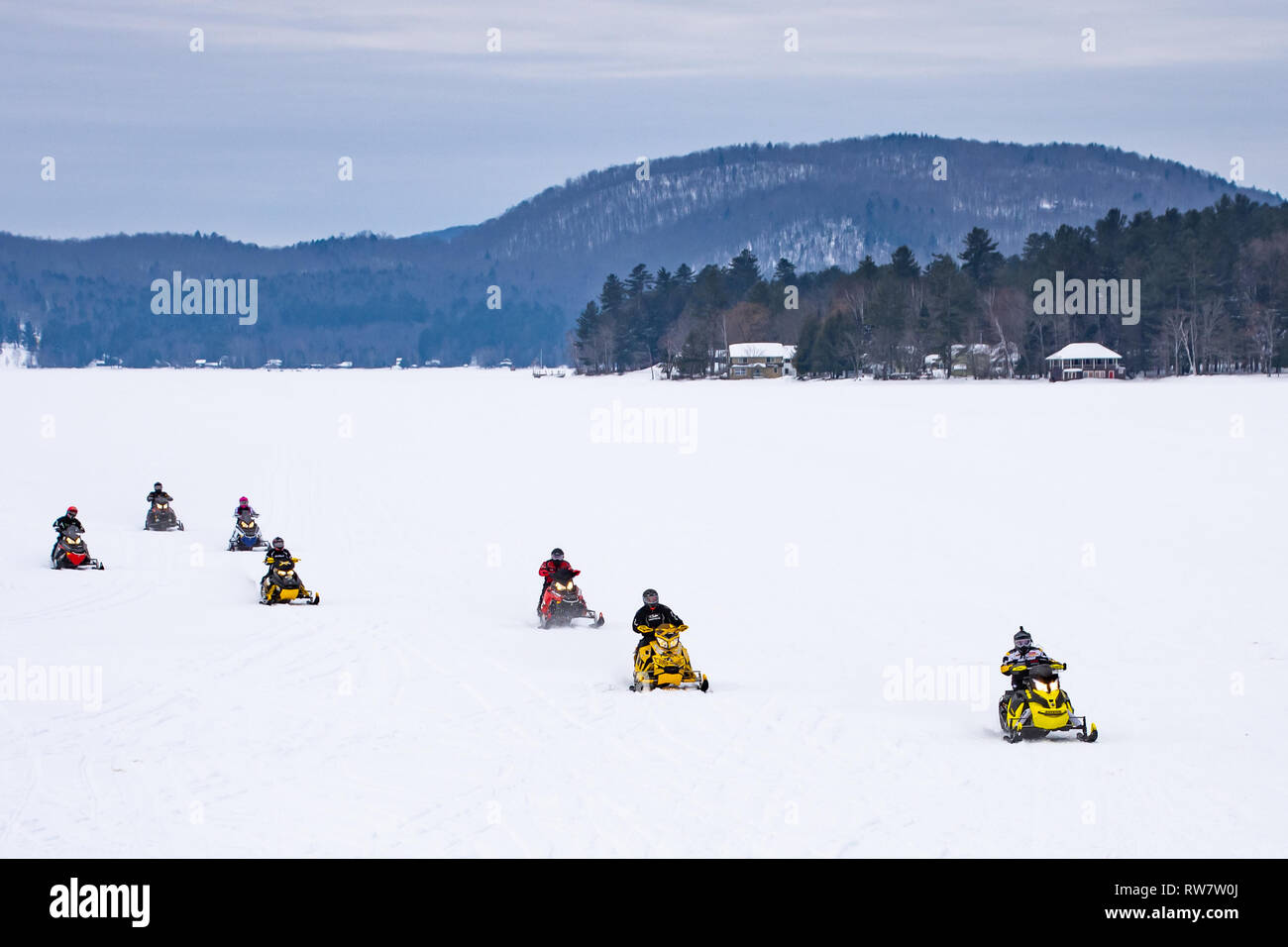 Un gruppo di 7 motoslitte racing attraverso il Lago Pleasant nelle Montagne Adirondack, NY USA Foto Stock