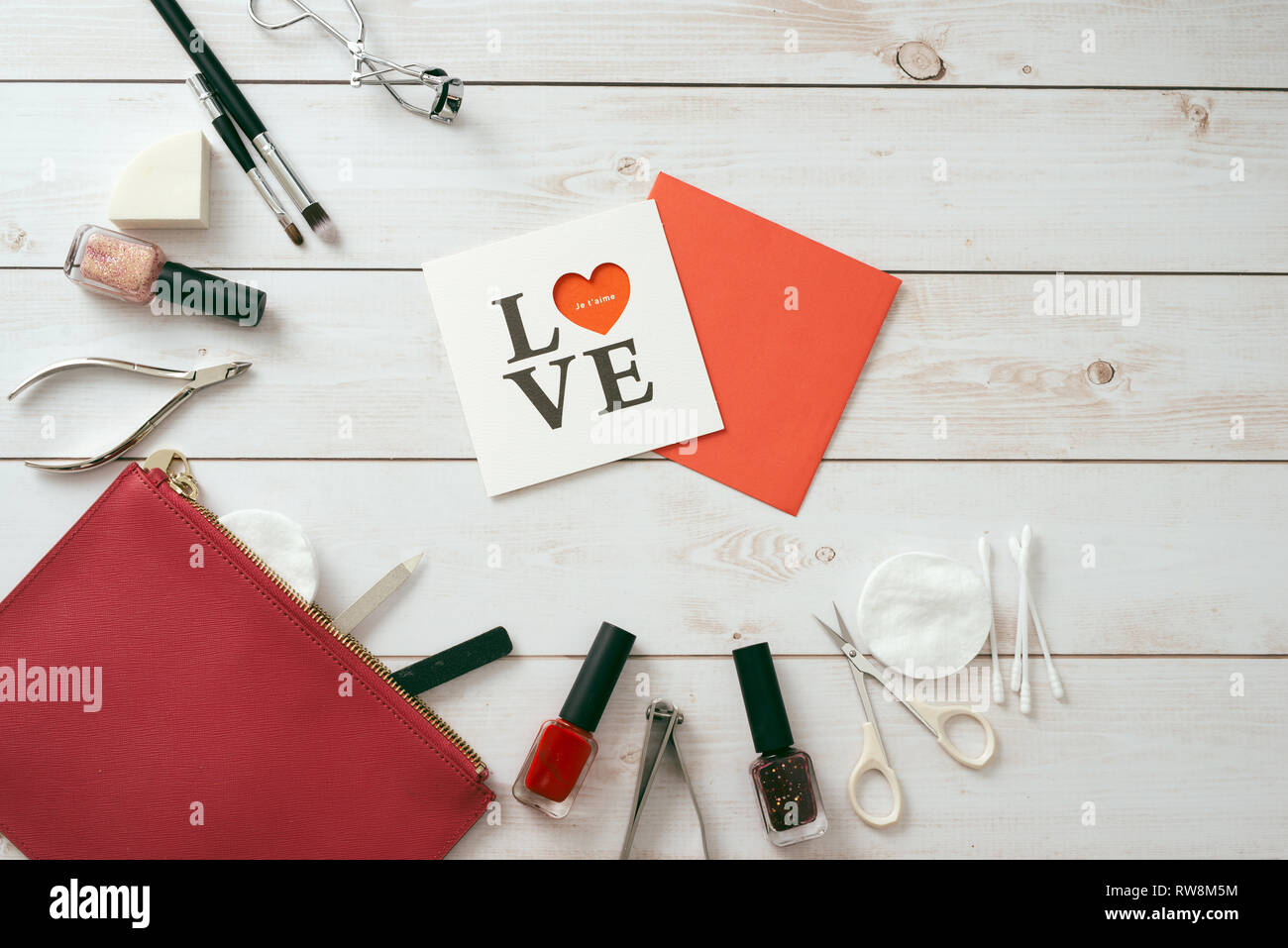 Carta bianca con un disegno a forma di cuore, set manicure e smalto per unghie su sfondo di legno. Il giorno di San Valentino. flatlay Foto Stock