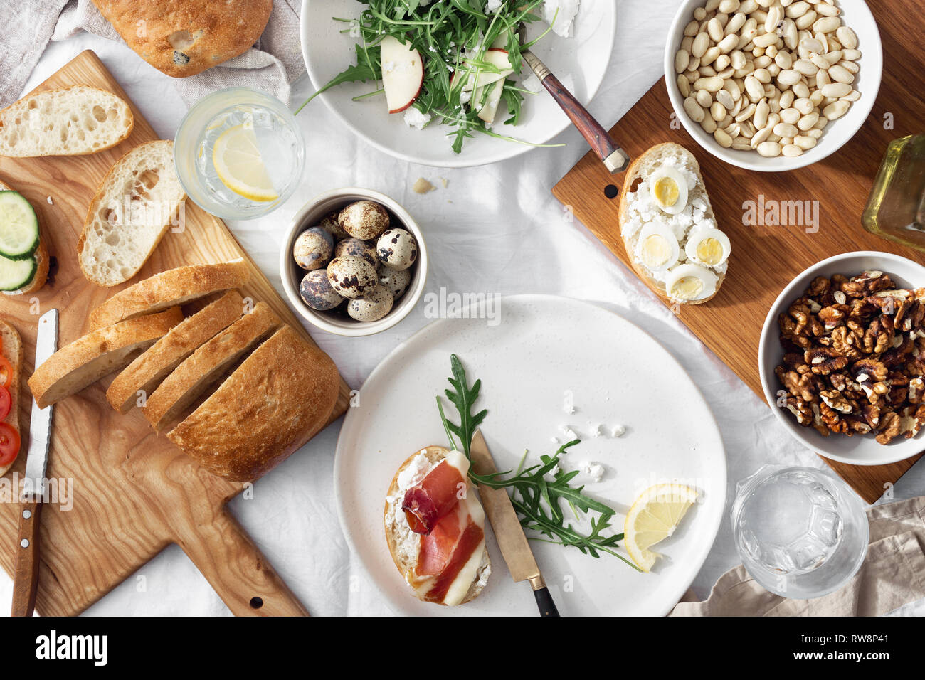Una sana prima colazione o il pranzo snack. Panini al prosciutto, verdure e insalata di rucola su sfondo chiaro, vista dall'alto Foto Stock