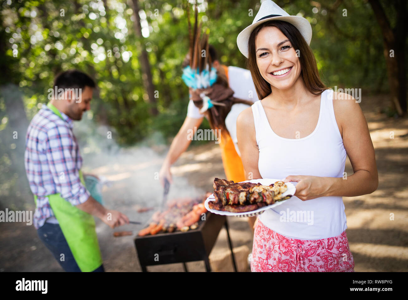 Amici fare barbecue e avente il pranzo nella natura Foto Stock