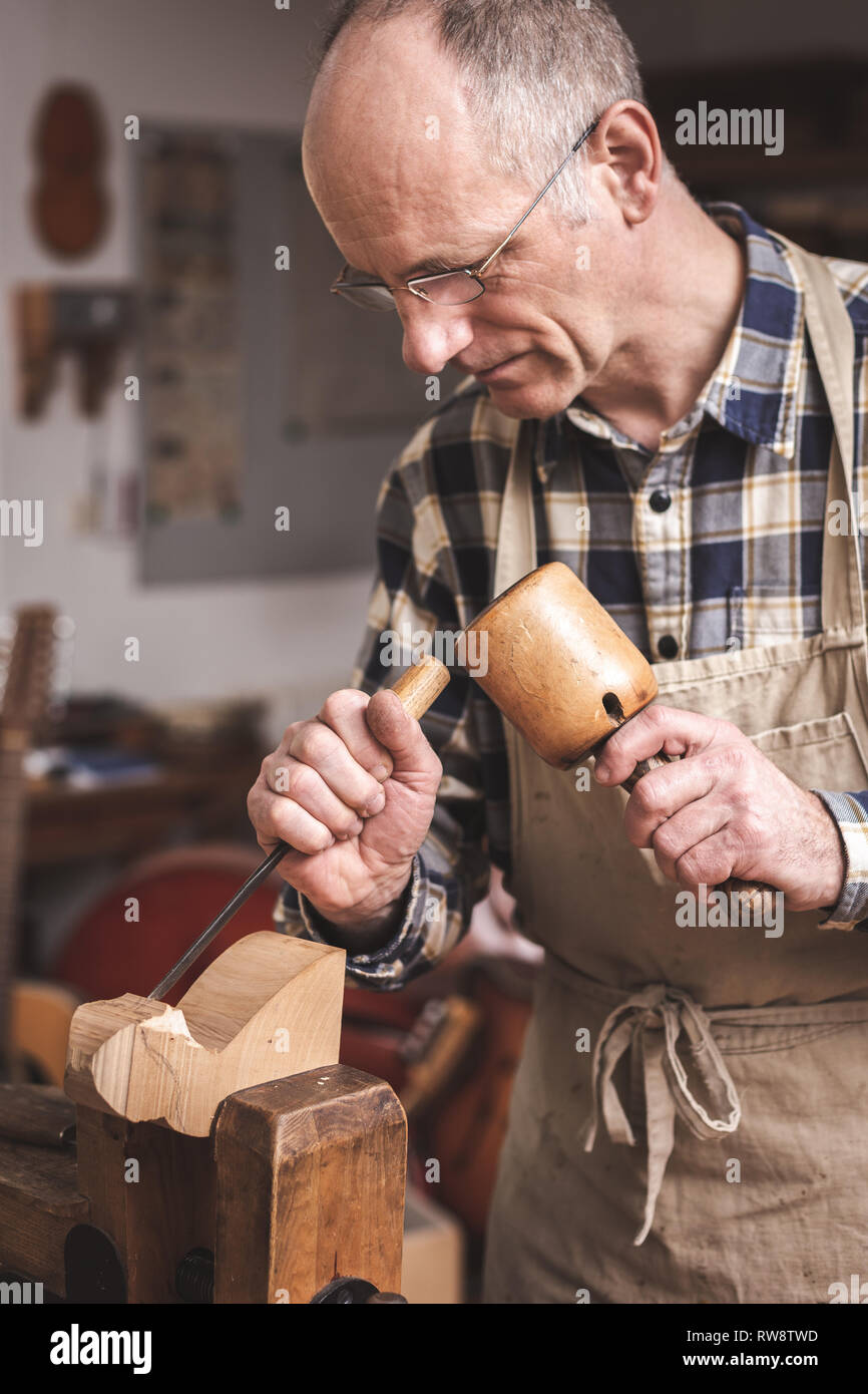 Scultore in legno lavora con uno scalpello e un mazzuolo Foto Stock