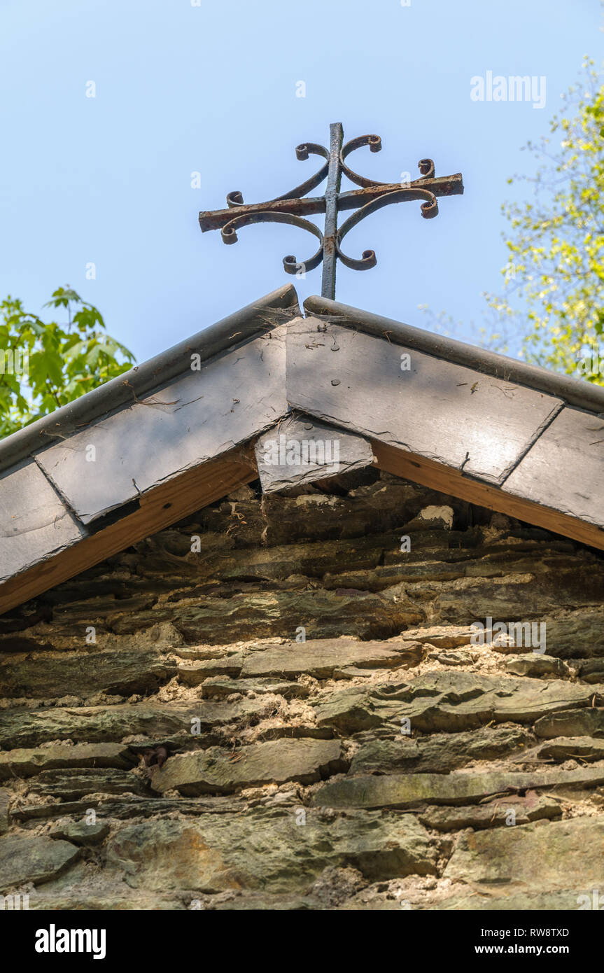 Close up rusty croce sul tetto di una piccola cappella sul ciglio della strada vicino a Maboge nelle Ardenne in Belgio. Foto Stock