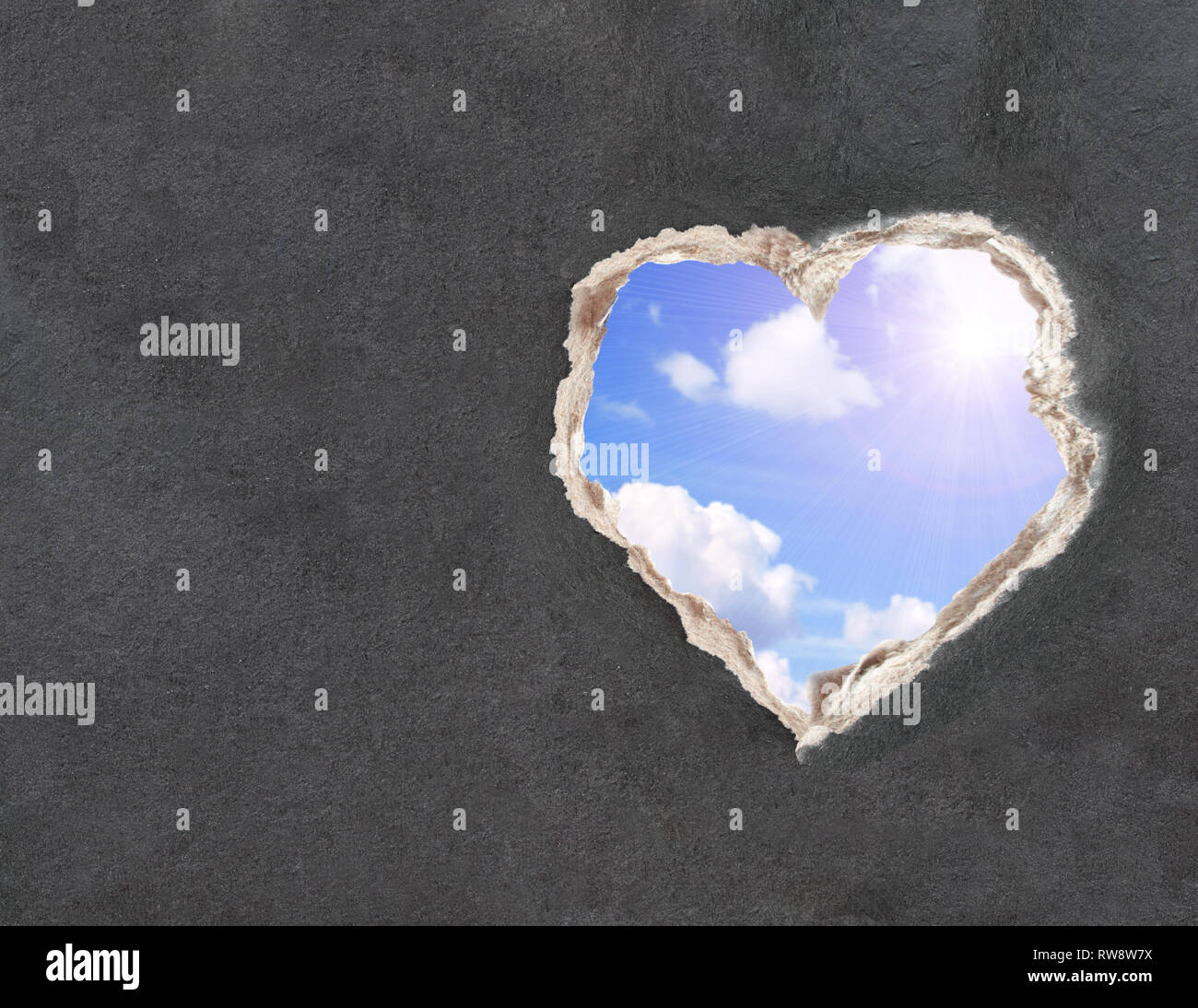 Il cielo blu con nuvole e sole luminoso in un foro carta nella forma di cuore. Mock up modello, copia spazio per il testo Foto Stock