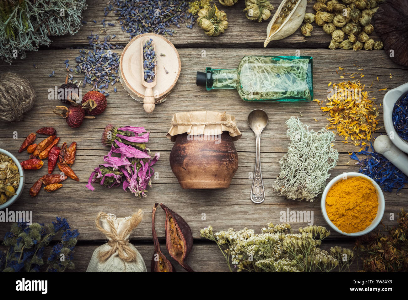 Asciugare le erbe medicinali, piante, radici, ingredienti per la fabbricazione di medicine a base di erbe farmaci, bottiglia di infusione, un vasetto di olio profumato, Malta su sfondo di legno. Foto Stock