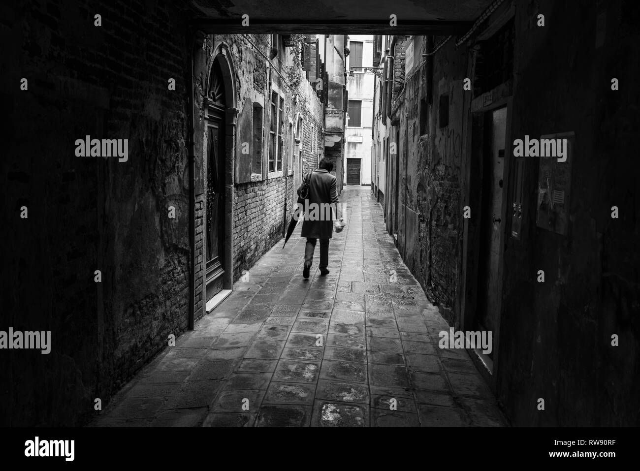 Un uomo a piedi una una stradina di Venezia. Strade di Venezia, Veneto, Italia Foto Stock