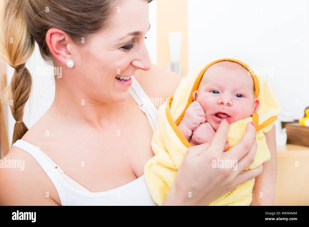Sorridente madre che porta il suo bambino avvolto in asciugamano Foto Stock