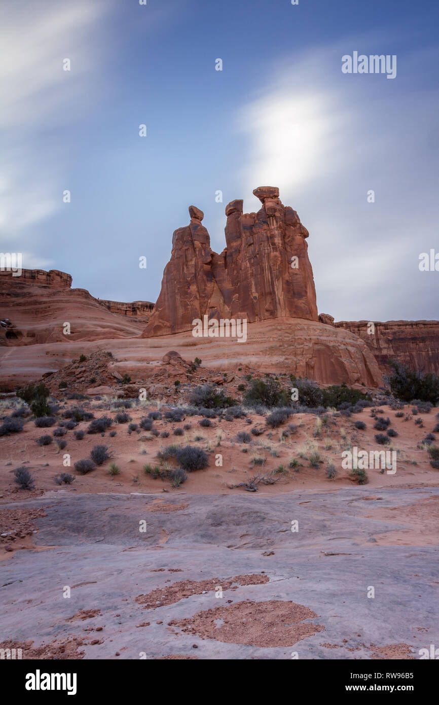 Giganti di roccia rossa caratteristica nota come le tre pettegolezzi nel Parco Nazionale di Arches, photo takin con un molto lento shuttterpeed sfumare il veloce movimento di nuvole Foto Stock