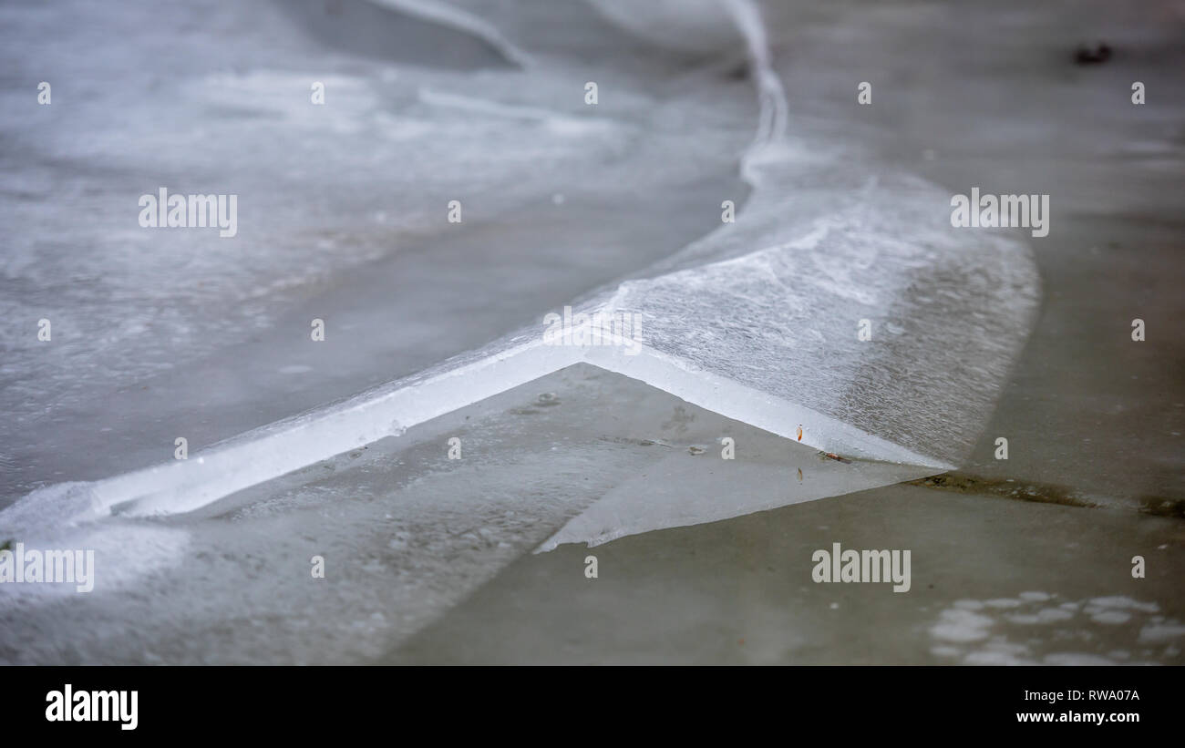 Uno spesso strato di ghiaccio sul lago ghiacciato a Vorderer Langbathsee. Belle montagne dalle vette innevate riflessa nelle acque cristalline del lago Foto Stock