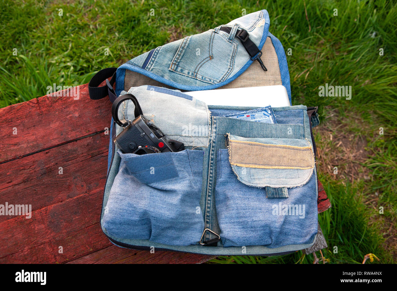 Vista superiore dello spazio di lavoro fotografo con fotocamera digitale nella fotocamera borsa, flash, caricabatterie, kit di pulizia, treppiede, scheda di memoria e accessorio fotocamera Foto Stock