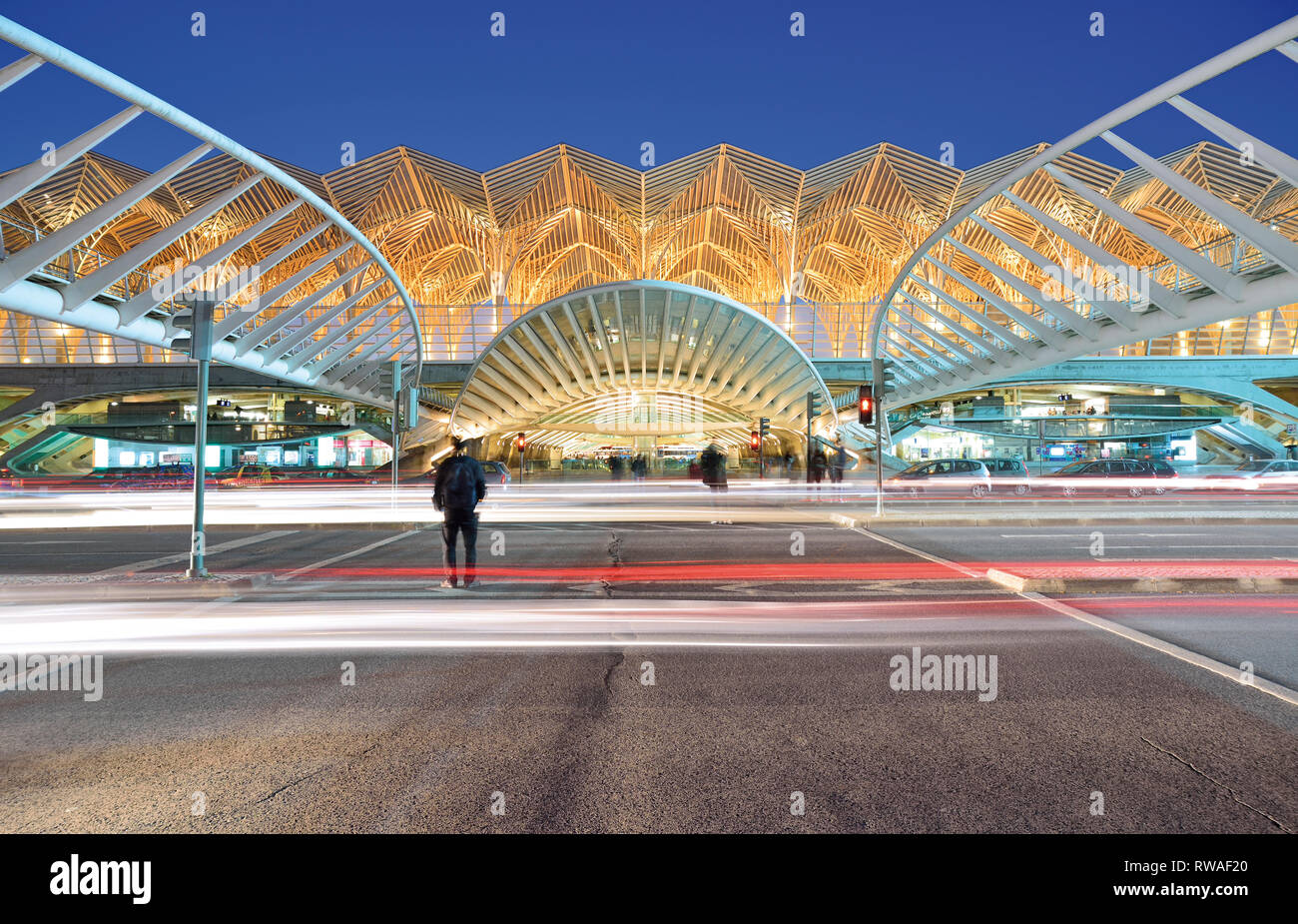 Le persone che attraversano le strada di ingresso principale della Stazione Gare do Oriente stazione di notte Foto Stock