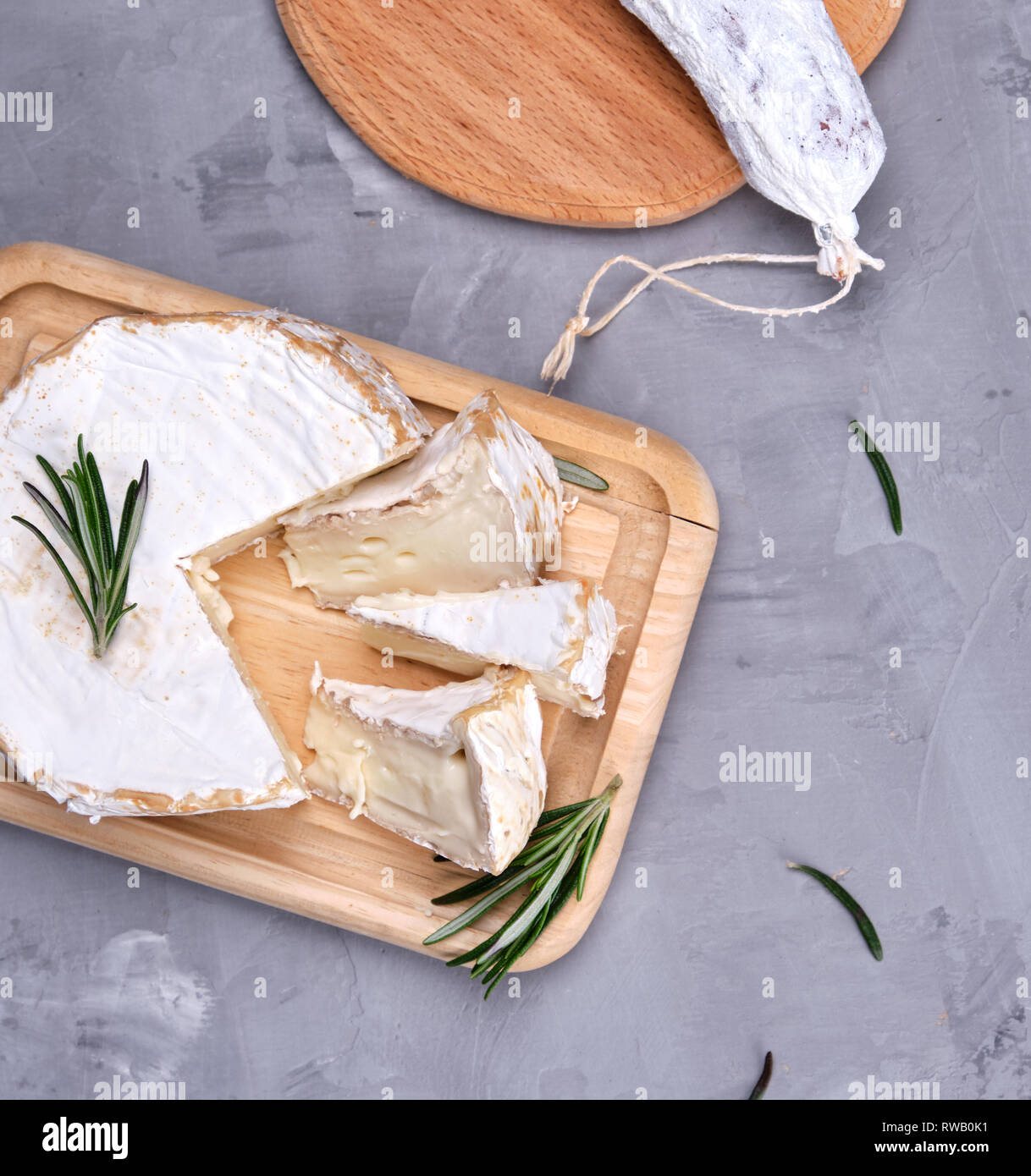 Tondo di Formaggio Brie e salsiccia su una tavola di legno e sfondo grigio, vista dall'alto Foto Stock