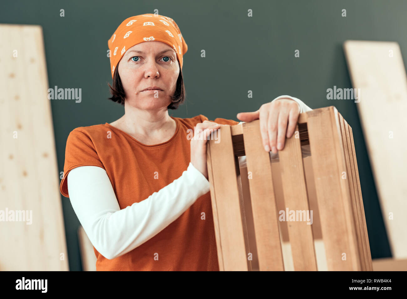 Orgoglioso carpentiere femmina in posa con finito di gabbia in legno per la sua piccola attività laboratorio di falegnameria Foto Stock