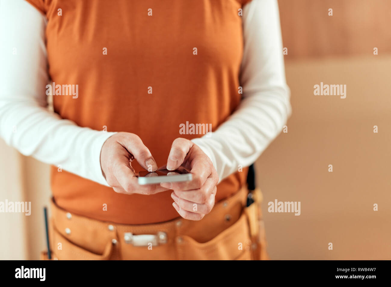 Falegname femmina utilizza lo smartphone, close up delle mani, il fuoco selettivo Foto Stock