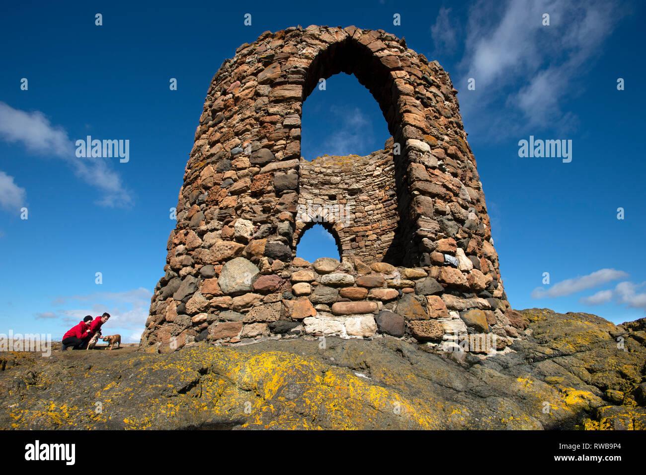 Due turisti e il loro cane crouch accanto alla signora della torre di Elie Fife sulla costa est della Scozia UK Foto Stock